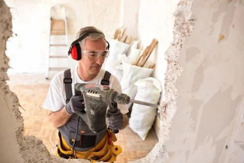 Senior worker using drill at contruction site Stock Photos