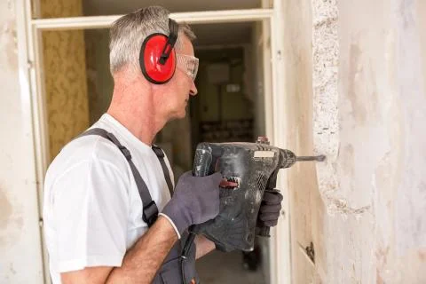 Senior worker using drill at contruction site Stock Photos