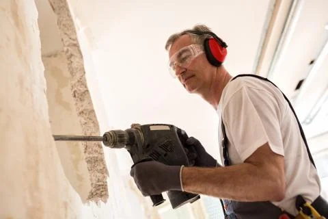 Senior worker using drill at contruction site Stock Photos
