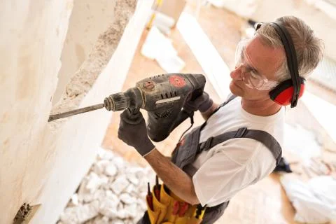 Senior worker using drill at contruction site Stock Photos
