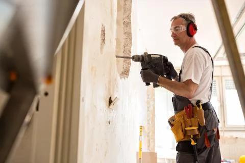 Senior worker using drill at contruction site 写真素材