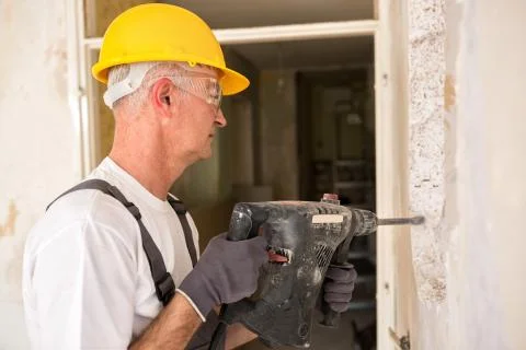 Senior worker using drill at contruction site Stock Photos