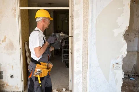 Senior worker using drill at contruction site Stock Photos