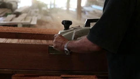 Senior worker using electric planer with wooden plank in carpentry workshop Stock Footage 79988625