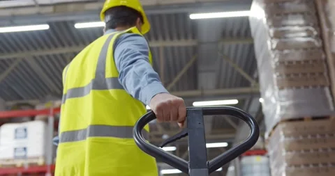Senior worker in warehouse using hand pallet stacker to transport goods. Stock Footage 151403547