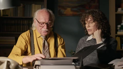 Senior Writer Discussing Script with Middle-Aged Female Colleague in Retro Study Video stock 312148486