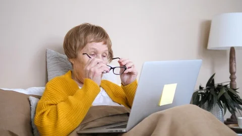 Seniors and Technology Concept. Elderly Woman Using Laptop Computer In Bed. Stockbeeldmateriaal 104586982