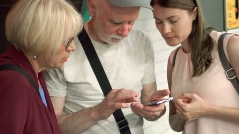 Seniors and their daughter standing in subway browsing in smartphone. Happy Stock Footage