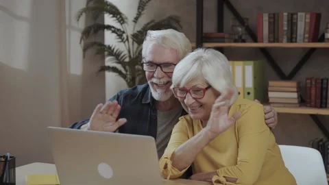 Seniors couple using a computer chatting via webcam and waving hands Video stock 140867570