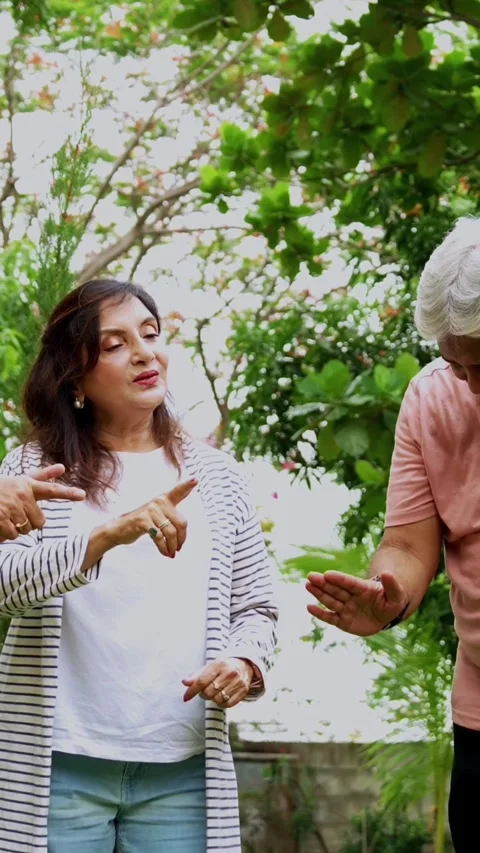 Seniors doing group huddle cheer together outdoors in garden Stock Footage 342387136