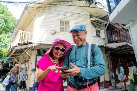 Seniors share laughter while looking at a smartphone on a lively street in .. Fotos Stock