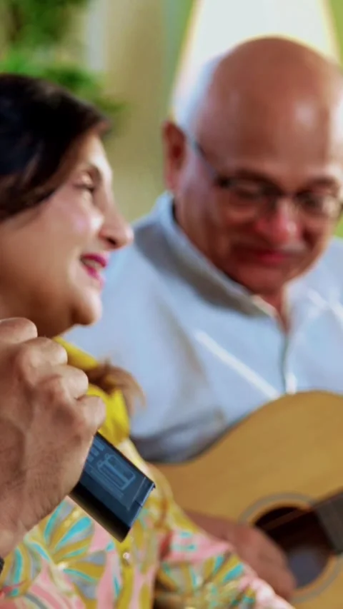 Seniors singing while playing guitar together during indoor musical reunion Stockbeeldmateriaal 342387286