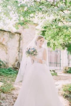 Sensitive bride under the veil is looking aside while spending time in the Stock Photos