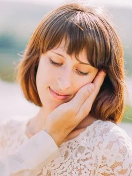 Sensitive close-up portrait of the bride. The hand of the groom is stroking her Stock Photos