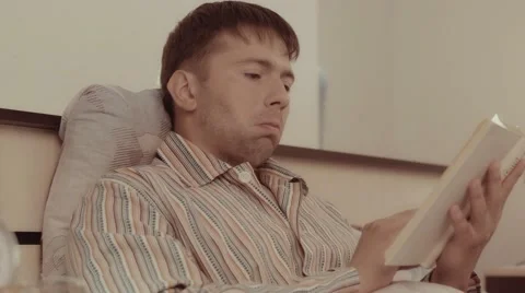 Sensitive young man reading a touching story in his book Stock-Footage 68420806