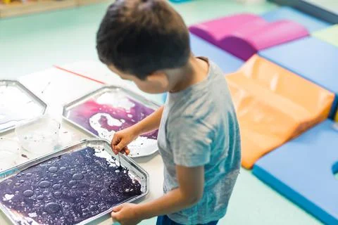 Sensory play for early brain development at nursery school. Toddler boy milk Foto stock