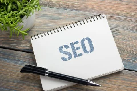SEO, online concept. Notepad with message, pen and flower. Office supplies on 库存照片
