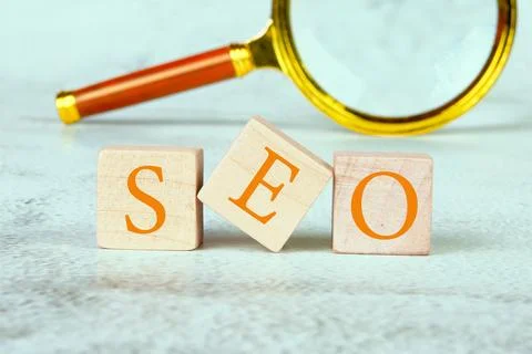 SEO Search Engine Optimization text on wooden cubes with a magnifying glass.. Stock Photos