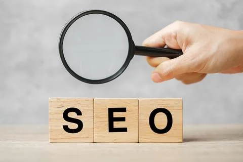SEO (Search Engine Optimization) text wooden cube blocks and hand holding m.. Stock-Fotos