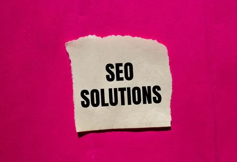 Seo solutions message written on ripped torn paper piece on pink background.  Stock Photos