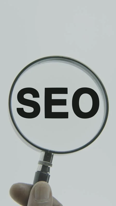 SEO text or word highlighted by a magnifying glass in a hand on a white Stock Footage 303516329