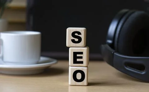 SEO -word on cubes on the background of the tablet, headphones and a white cu Stock Photos