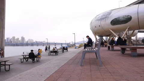Seoul citizens sitting on bench, reading, talking, relaxing outside Stock Footage 95003755