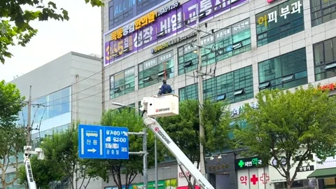 Seoul, October 10, 2025. A worker in safety gear stands in an elevated hydraulic Stock Footage 319087630