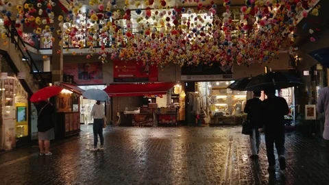 Seoul - People with umbrellas at rainy night walking in courtyard at Insadong Stock Footage