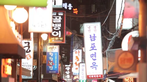 Seoul sci fi backstreet with glowing neon signs and pedestrians tilt Stock Footage 100594366