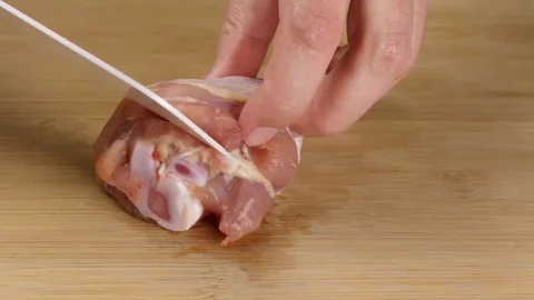 Separating chicken meat from bone for making fillets and cutting and slicing as Stock Footage 107510877