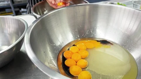 Separating egg yolk from white by hand into a stainless steel bowl. Stock Footage 346605519