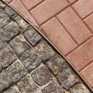 Separation of a metal strip of two types of pavers. View from above. Stock Photos