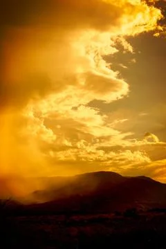 Sepia colored storm cloud climbing and wrapping around a mountain. Stock-Fotos