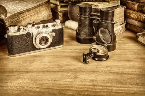 Sepia styled image of camera with compass and books Stock Photos