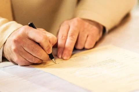 Sepia tone image of a man signing a document Stock Photos
