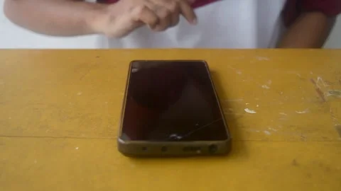 A sequence shows a man hands interacting with a black smartphone on a yello.. Stock Footage 332912346