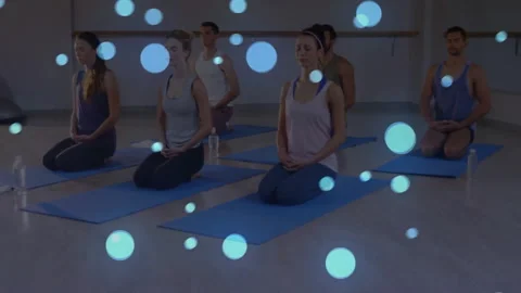 At sequence start yoga group kneeling on blue mats settling into meditation with Видео 313570991