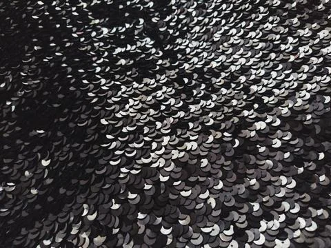 Sequin fabric. Black sequins with white and gray sheen. Reflection of light o Stock Photos