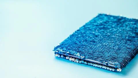 Sequin notebook on blue background, copy space Stockfoto's
