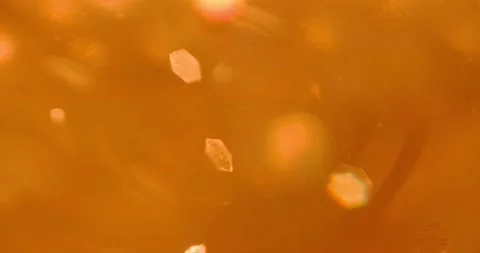 Sequins floating in a liquid highlighted in orange Stock Footage 166653921