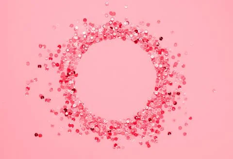 Sequins multicolored confetti lined in round frame pink background. Abstract Stock Photos