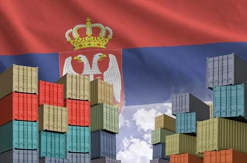 Serbia flag and big stack of shipping cargo containers in docks with sky Stock Photos
