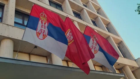 Serbian flags sway gently in a soft spring breeze, mounted on a Yugoslav-style 스톡 동영상 310942149