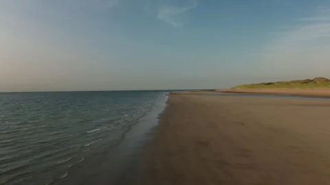Serene Beach Landscape with Gentle Waves and Lush Coastal Dunes Vídeos de archivo 295947656