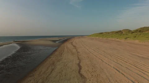 Serene Beach Landscape with Tranquil Waves and Rolling Hills Stock Footage 295951173