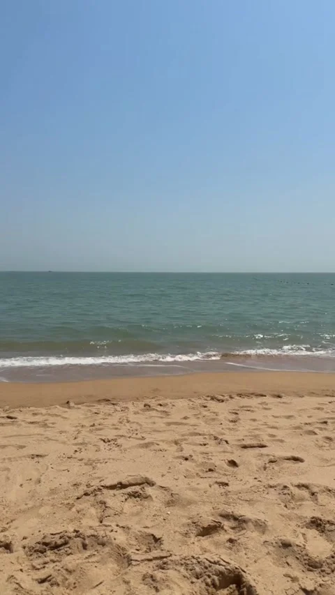 Serene beach scene with calm ocean waves gently rolling onto the golden sandy Vídeos de archivo 334163330