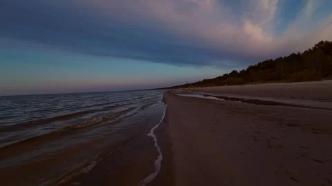 A serene beach scene at dusk, featuring calm waves lapping against an empty Video stock 282757912