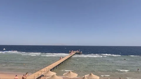 A Serene Beach Scene Featuring a Long Pier Stretching Over Calm Blue Waters Stock-Footage 330099566