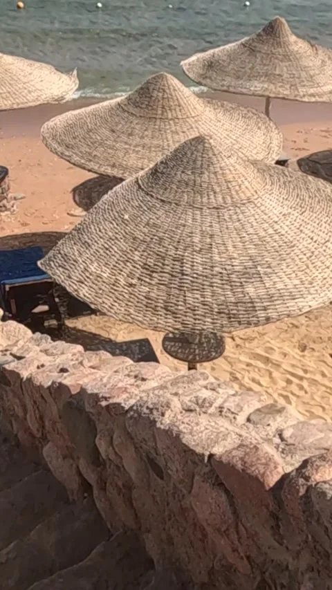A Serene Beach Scene Featuring Thatched Umbrellas and Stone Steps Leading to a 库存影片 330095569